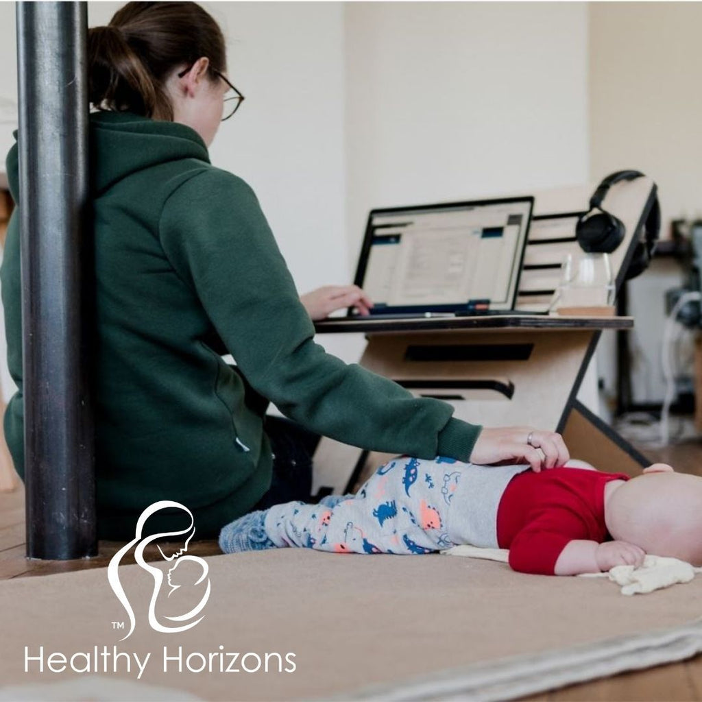 Young mom working on laptop with napping baby